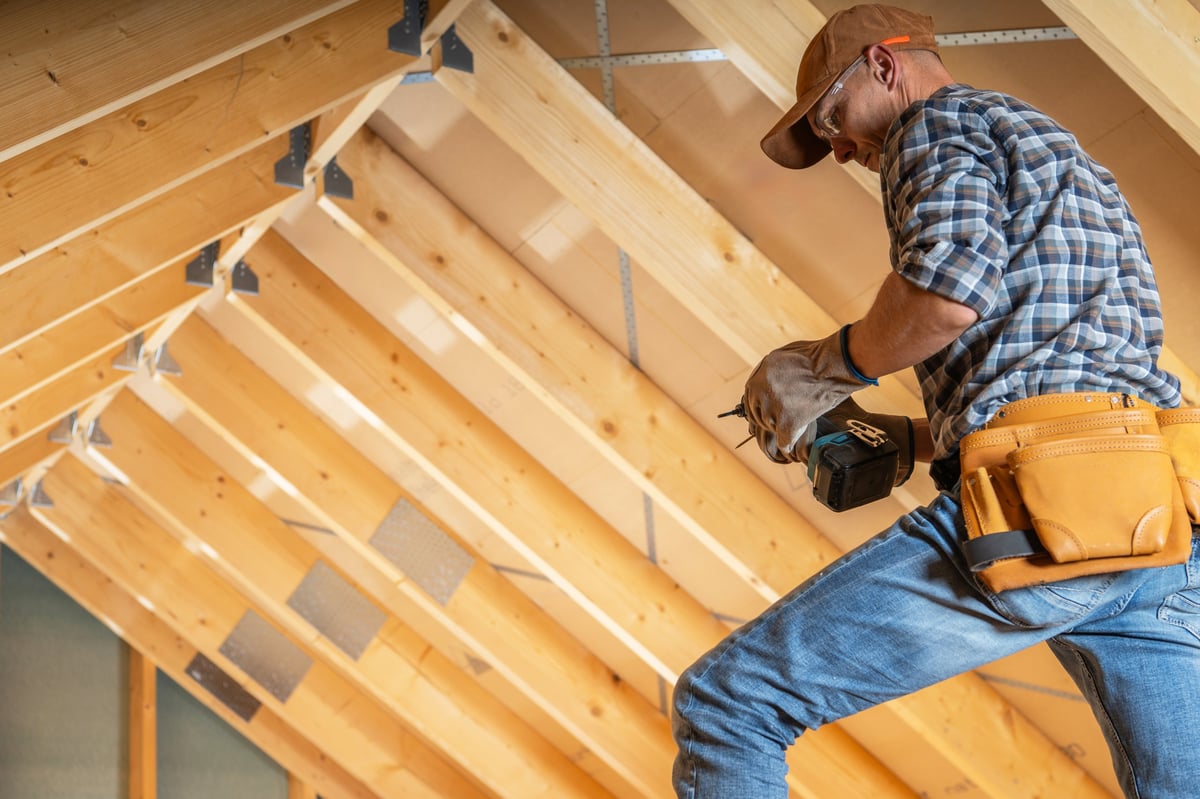 A construction worker installing wooden beams during a home renovation