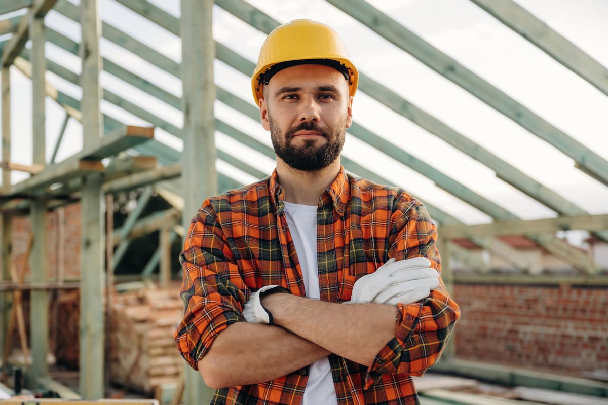 Construction worker wearing a hard hat working on a house roof